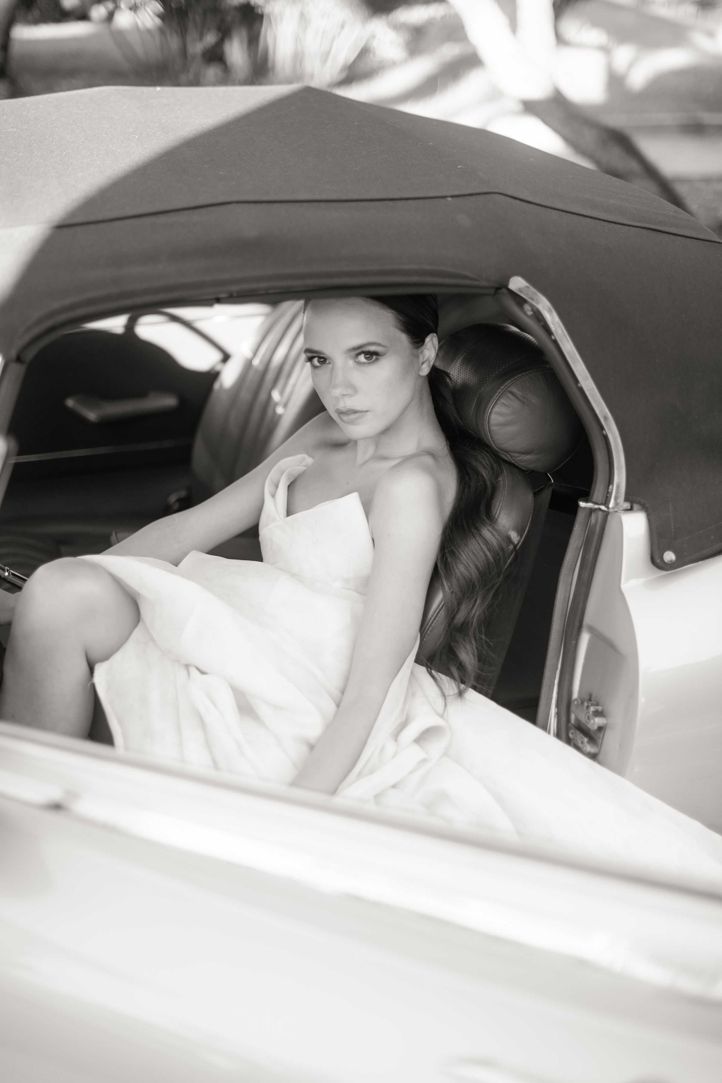 la mariée est dans la voiture et regarde le photographe